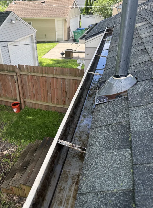 Freshly cleaned white aluminum gutter system showcasing clear channels and proper drainage slope along a residential roofline