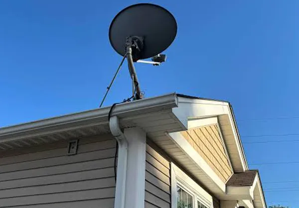 Old satellite TV dish mounted to residential roofline ready for removal and disposal