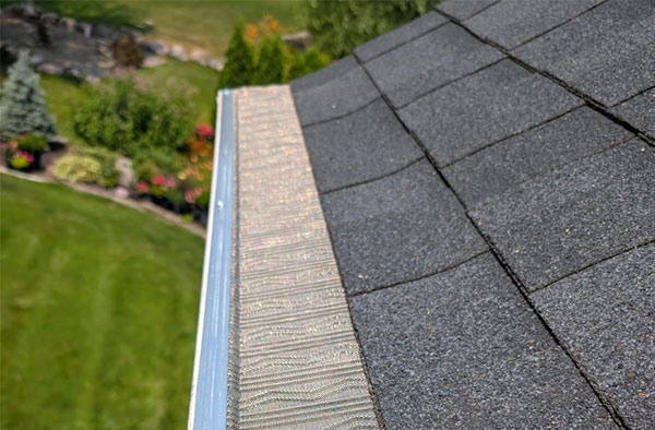 Mesh gutter guard system installed on a white aluminum gutter along a residential roofline